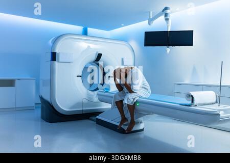 CT scanner gantry dominating left side and motorized exam table extending right with blue LEDs Stock Photo