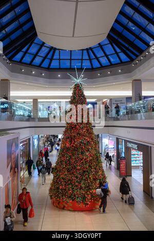 Toronto, ON, Canada - December 24, 2025: Shoppers walking past a large decorated Christmas tree inside a multi level shopping mall during the holiday Stock Photo
