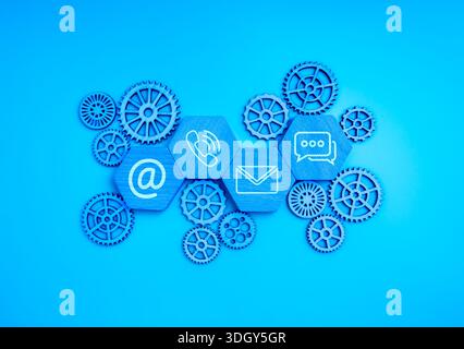 Contact us concept with communication icons on hexagon blocks with gear mechanism on blue background, representing workflow management, support system Stock Photo