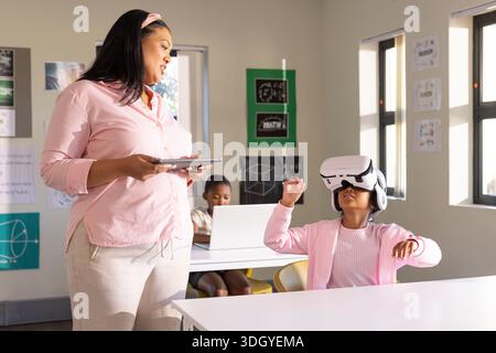 African American teacher holding tablet guiding female student wearing white VR headset, copy space Stock Photo