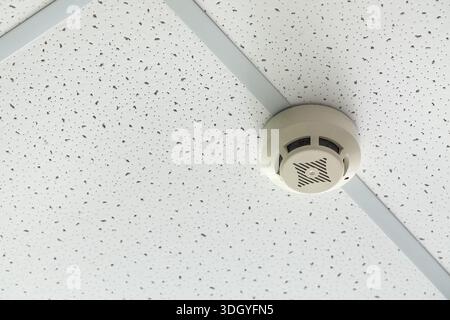 Modern smoke detector on ceiling in room, closeup Stock Photo