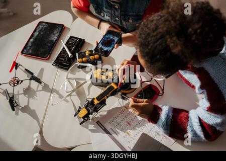 High school students working on robotics project, using online AI app to answer questions. Stock Photo