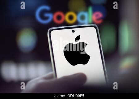 Apple logo on a phone, in the blurred background the logo of Google Stock Photo
