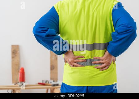 Man, architect and hands in back pain, accident or posture after construction injury on site. Rear view of male person, contractor or engineer with so Stock Photo