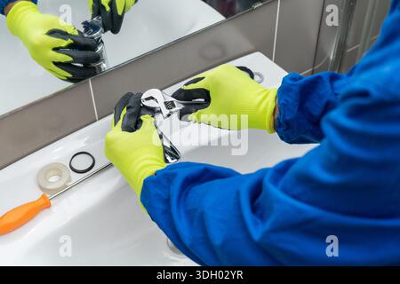 Repair man plumber installing a faucet in a bathroom's sink - home repairment concepts Stock Photo