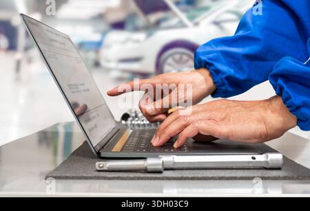 Close-up of hands of manager at the auto repair shop using a laptop in the work place to prepare and tune up a vehicle. Stock Photo
