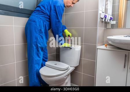 Latin American plumber fixing a toilet in the bathroom at home.Home repair concepts Stock Photo