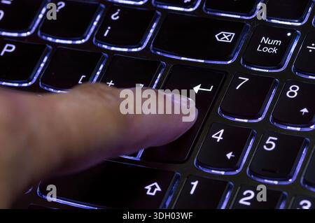 Finger presses the input key on the blue keyboard. Selected focus. Stock Photo