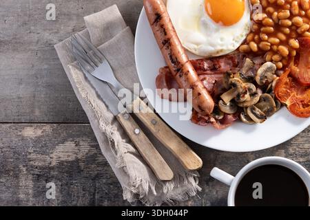 Full English breakfast with fried egg, bacon, sausages and beans on wooden table Stock Photo