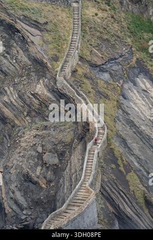 Endless zigzagging stone steps on a rocky mountain slope by the sea. Stock Photo