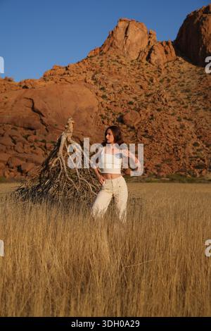 Young woman standing in an African savannah with mountain backdrop Stock Photo