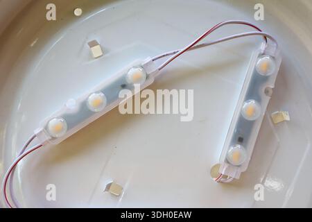 Close up modern LED module light strips with wires for ceiling lamp or lighting fixture, displaying bright and efficient energy saving technology for Stock Photo