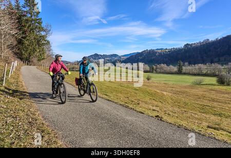elderly couple rides electric mountain bikes on a trail in the Allgäu Alps near Oberstaufen in Bavaria. The scene depicts a wintry mountain landscape Stock Photo
