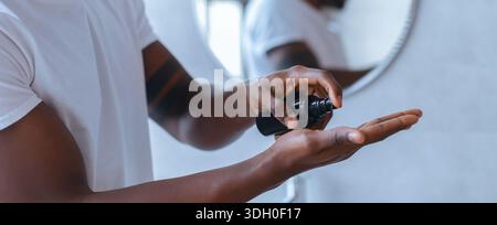 Man Applying Skincare Product in Bathroom While Looking in Mirror Stock Photo