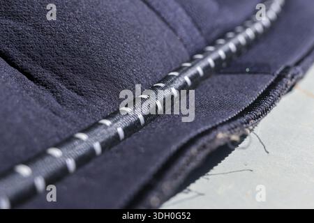 Close up detail of dark blue quilted fabric texture showing heavy duty stitching and black white striped cord trim featuring strong durable constructi Stock Photo