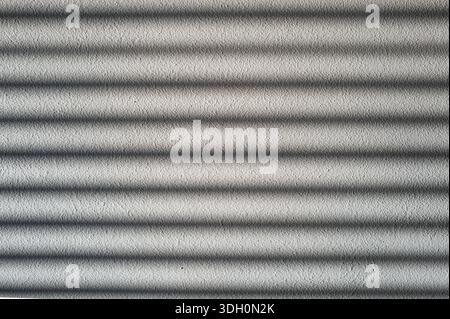 Rough cement wall in grey color covered by shadow in stripped lines from the sunlight through the window. Stock Photo