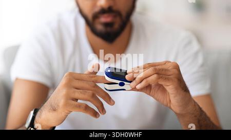 Unrecognizable man using pulse oximeter at home Stock Photo