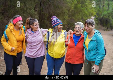Multiracial women having fun during trekking day into the wood - Escape to the nature and travel concept - Focus on center female faces Stock Photo