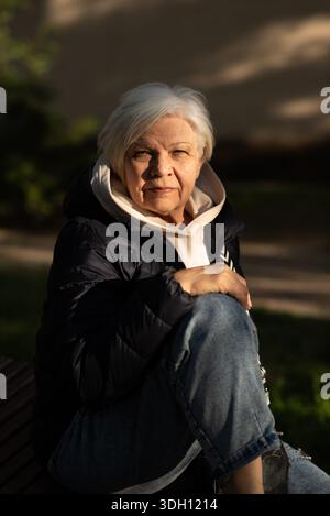 Close-up portrait of an older woman sitting outdoors in golden hour light. Stock Photo