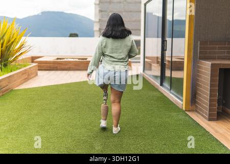 Young woman with prosthetic leg enjoying a moment of relaxation on a rooftop garden Stock Photo