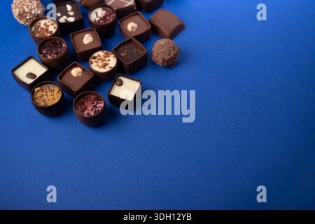 assorted gourmet chocolate pralines and truffles on a vivid cobalt-blue background, showcasing varied shapes, textures, nuts and ganache toppings in a Stock Photo