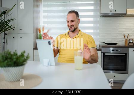 Man having video call on tablet in home kitchen Stock Photo