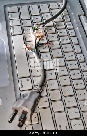 Still life of a frayed computer power cord on a laptop keyboard, 2026, United States Stock Photo