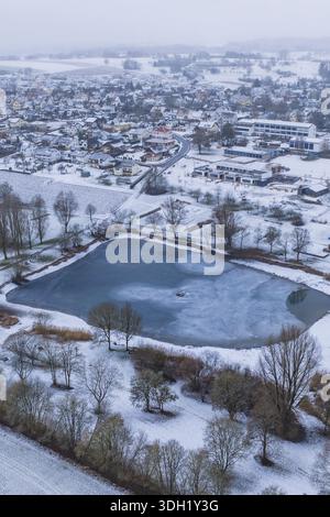 Snowy village with frozen lake seen from above on a grey day, Empfingen, Freudenstadt district, Germany Stock Photo