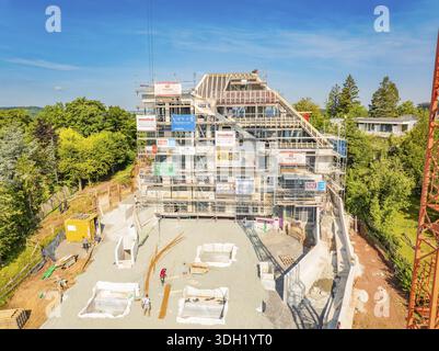 Large construction site with scaffolding around a multi-storey building and building materials on site, carpentry construction, roof extension, renova Stock Photo