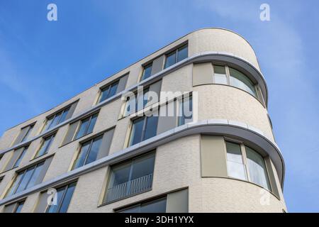 Modern building, detailed view of a residential building, apartment building with large glass facade and rounded corners under clear blue sky, Tuttli Stock Photo