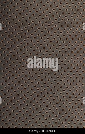 dark smooth perforated leather for shoe production , a large number of equal holes in natural leather close up Stock Photo