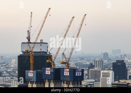 Over the rooftops of Bangkok, construction of a new high-rise building with construction cranes, view from the Moon Bar on the roof terrace of the Ban Stock Photo