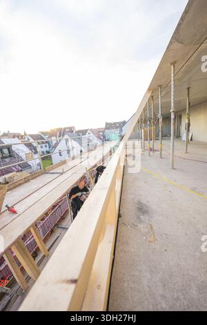 Worker on a construction site looking at residential buildings and the half-finished interior, carpentry construction, roof extension, renovation, Stu Stock Photo