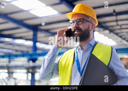 Warehouse manager with safety helmet making phone call. Stock Photo