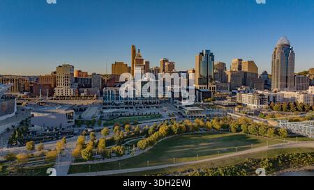 Aerial view of Cincinnati's skyline reflects the warm glow of the setting sun on the buildings and the lush greenery of the park below, Cincinnati, Oh Stock Photo