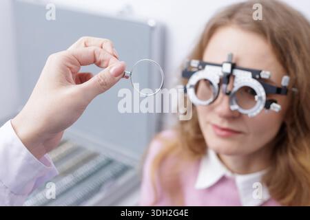 Optometrist demonstrates test lens while patient wears trial frame during vision exam, ideal for clinic website, eye care ads, and optometry service m Stock Photo