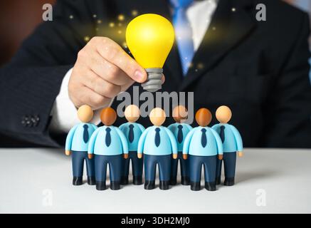 A lightbulb of an idea shines over a team of office workers. A leader inspires his subordinates. A project manager. Creative leadership concept, motiv Stock Photo
