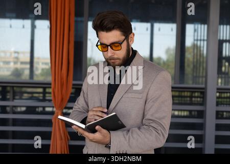 Professional man working on his notes in a notebook at an outdoor terrace Stock Photo