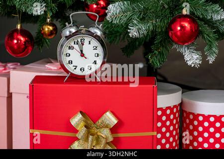 Alarm clock and gift boxes under christmas tree. Christmas background Stock Photo