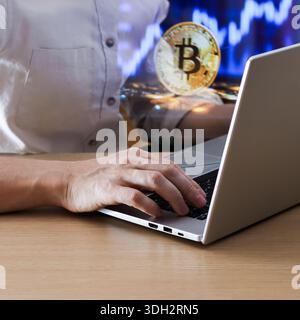 Focused shot of typing on notebook computer with glowing coin and market data overlay. Stock Photo