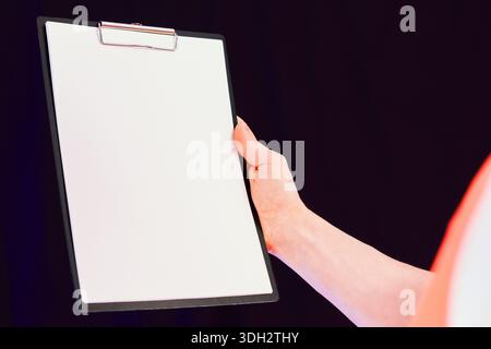 Safety worker's hand holding empty clipboard for insertion of text or graphics in photo Stock Photo