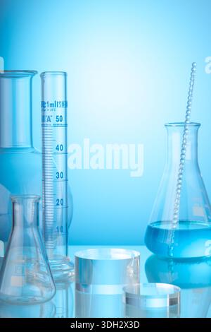 Science and medical background with transparent round podium, lab glassware filled liquid on blue background. Space for products presentation. Stock Photo