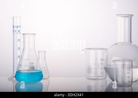 Glass flasks and cylinder beakers in medical science lab on white background. Space for products presentation. Stock Photo