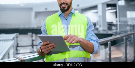 Construction Worker Using Tablet at Building Site During Work Hours for Project Management Stock Photo