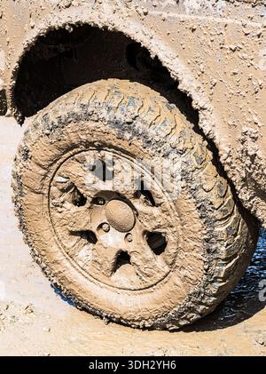 Extremely dirty off-road car wheel after driving heavy off-road in the rain Stock Photo