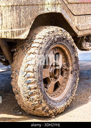 Extremely dirty off-road car wheel after driving heavy off-road in the rain Stock Photo