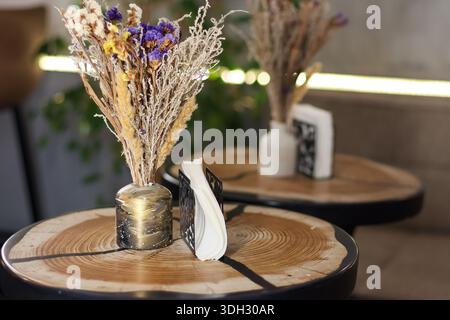 Close-up of decorative dried bouquets in vases with napkins on rustic wood slice tables. Stock Photo