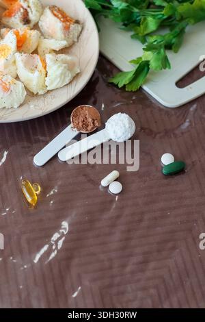 Upright composition featuring poached eggs on left, measuring spoons with powders and assorted capsules on right surface. Stock Photo