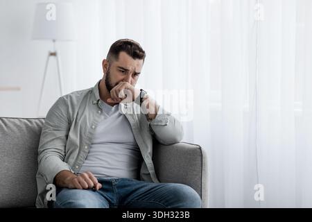 Sad handsome man crying presses hand to face Stock Photo