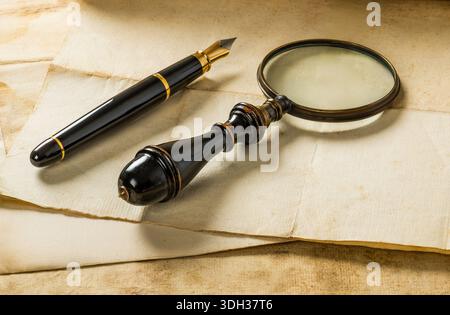 Fountain pen and magnifying glass with old sheets Stock Photo